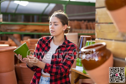 Young woman chooses flower pots for indoor plants
