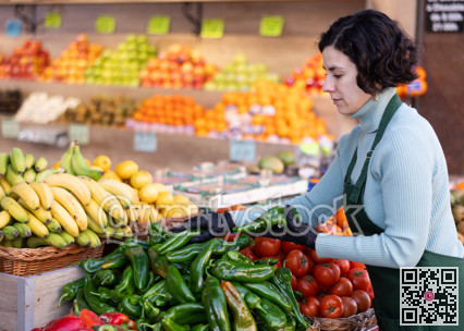 Adult woman seller puts bell peppers on display