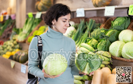 Shopping for vegetables in a supermarket - man selects cabbage