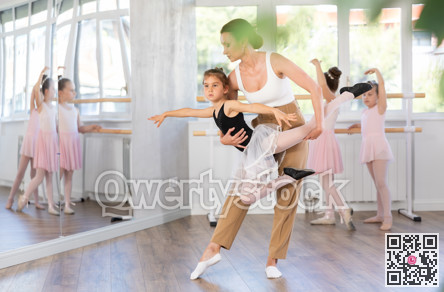 Woman teacher corrects movement of girl dancer