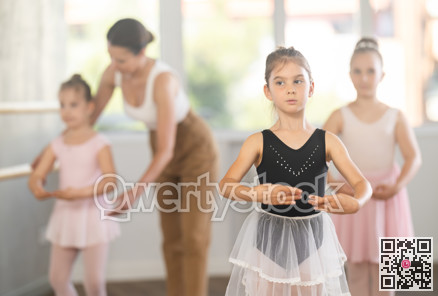 Girls in ballet class perform first position with correction of female mentor