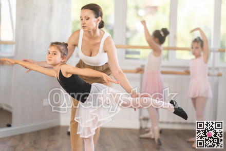 Woman teacher corrects movement of girl dancer
