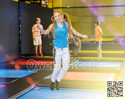 Teen girl jumping on trampoline on indoor inflatable playground