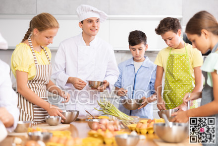 Friendly young chef running culinary courses for group of children