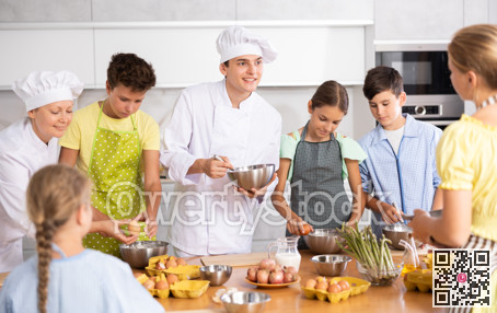 During cooking lesson, male cook tells children about culinary rules, woman assistant helps child