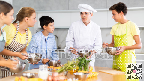Group of teenagers and friendly chef cook cooking in modern kitchen. Learn to beat raw eggs