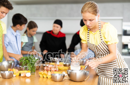 Cooking course - portrait of a girl in an apron who is learning to beat eggs to make pancakes at cooking class