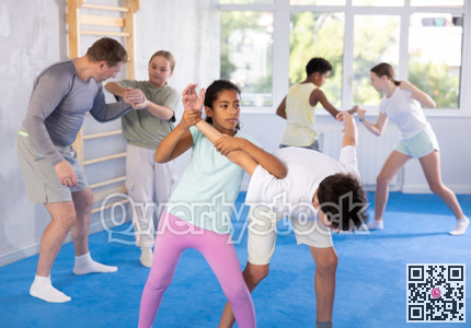 Black tween girl practicing armlock in training bout with boy during self defence course