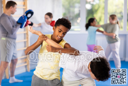 African teenager practicing painful armlock in sparring with boy at self defence training