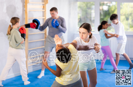 Preteen children pairs learning strength self-defense in gym