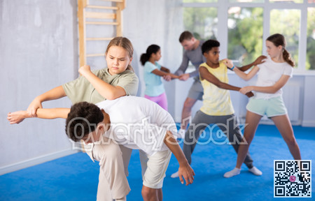 Girls and boys learns to do power grip with trainer during a self-defense lesson in gym