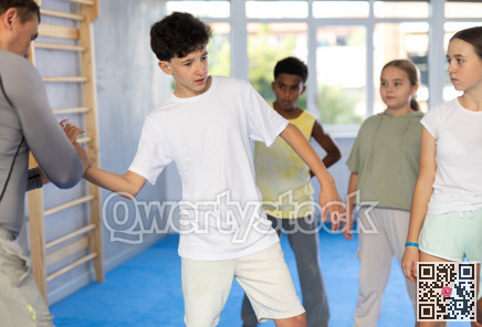Self-defense trainer shows group of multinational children how to do painful arm grip correctly