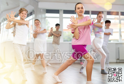 Team of teenagers rehearsing modern dances in dance hall
