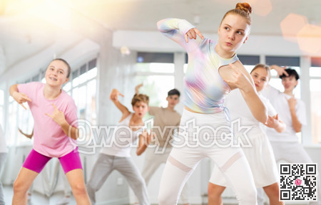 Team of teenagers rehearsing modern dances in dance hall