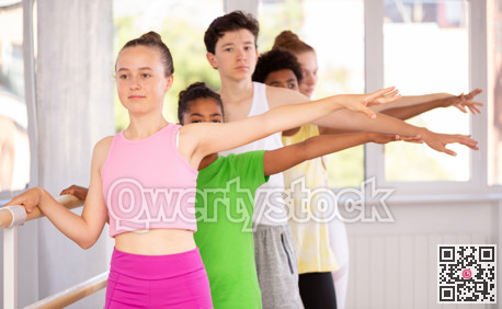 Teenage girl practicing position holding by ballet barre during workout session