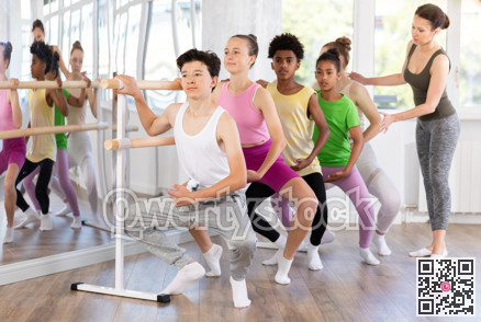 Teenager practicing grand plie at barre at group ballet class
