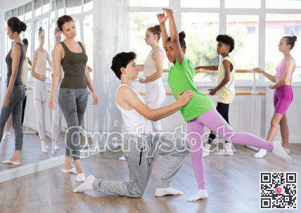 Teenage girl and boy practicing arabesque position of ballet in dance studio
