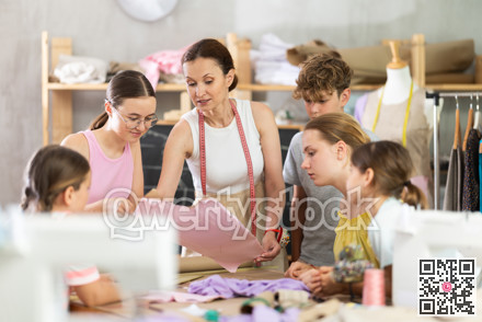 Female teacher at the blackboard explains to children how to make patterns and sew dress