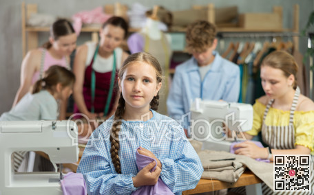 Teenage girl holding sewing work in clothing course