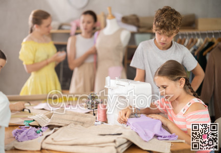Girl sews on a sewing machine. Boy watches and learns