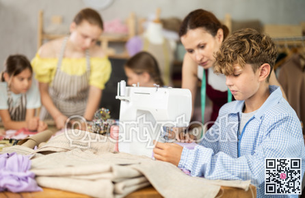 Preteen boy working at machine during group sewing course for kids