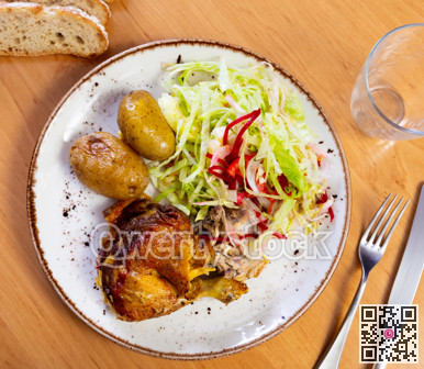 Fried chicken thigh garnished with salad of fresh vegetables and potatoes