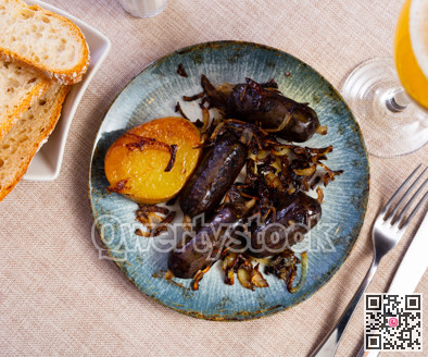 Several small black puddings sausages are toasted fried with onion rings