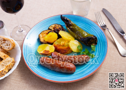 Grilled sausages served with baked potato, pepper and eggplant