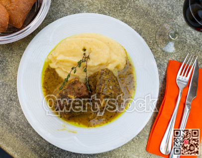There is portion of roast beef with mustard sauce gravy on plate and side dish of mashed potato