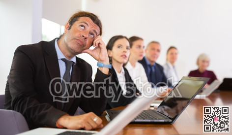Middle aged white business man yawning at boring meeting