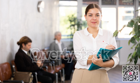 Young woman in business clothes with folder posing in office