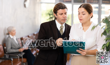 Focused manager discussing documents with young female assistant