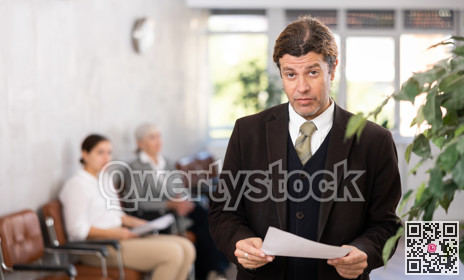 Adult man posing with documents in office