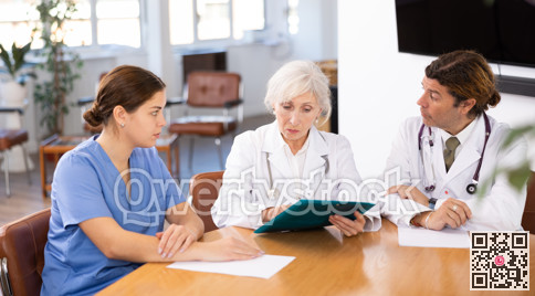 three positive doctors are sitting at table animatedly and actively discussing current work