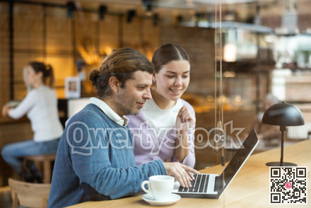 Man and woman looking at laptop screen while having lunch at bar counter of cafe