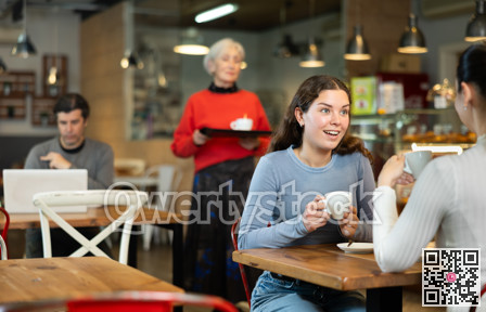 Girl in cafe sits opposite female companion, has nice conversation