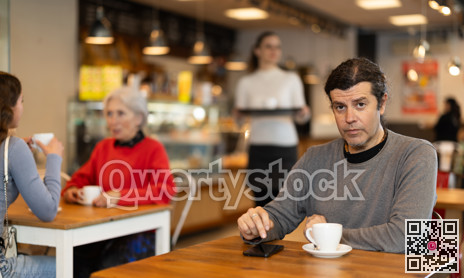 Man drinking coffee and looking at mobile phone screen. Waiting for meeting