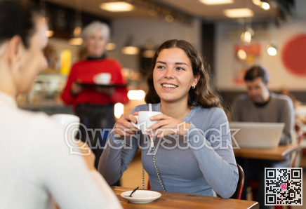 Girl in cafe sits opposite female companion, has nice conversation