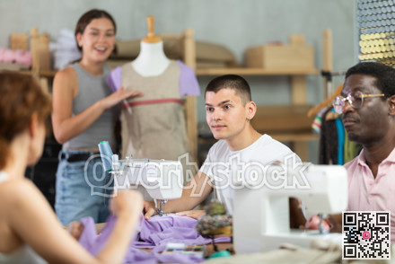 Young guy talking with woman and sewing, other working with mannequin