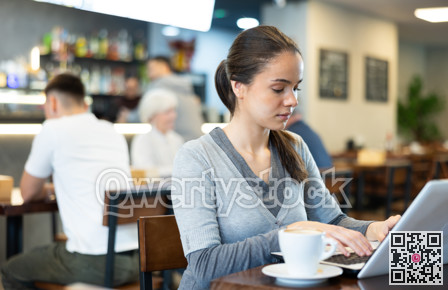 Girl works on a laptop and drinks coffee in cafe interior