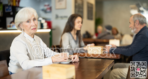 Senior woman whiles away time and drink coffee in cafe