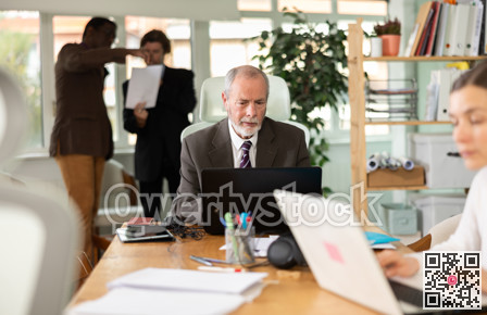 Elderly man working in office with laptop