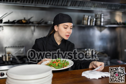 Woman cook checks paid check and cooked dish in kitchen