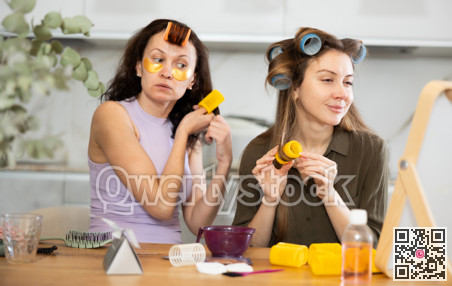 Two women curling their hair with curlers