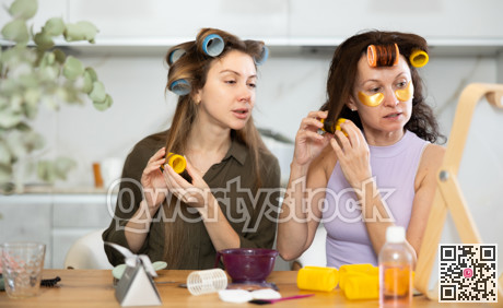 Two women curling their hair with curlers