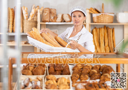 Positive female bakery employee offering bread and different baguettes for sale