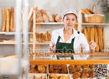 Female baker holds basket with finished products, shows different croissants.