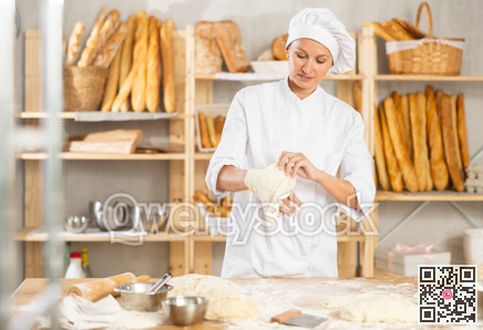 Professional female baker preparing pizza dough in bakery