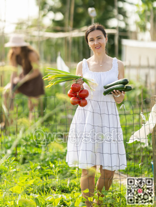 Adult woman with vegetable harvest in cottage garden