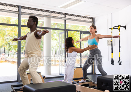 Man and woman doing exercises in pilates gym with man instructor